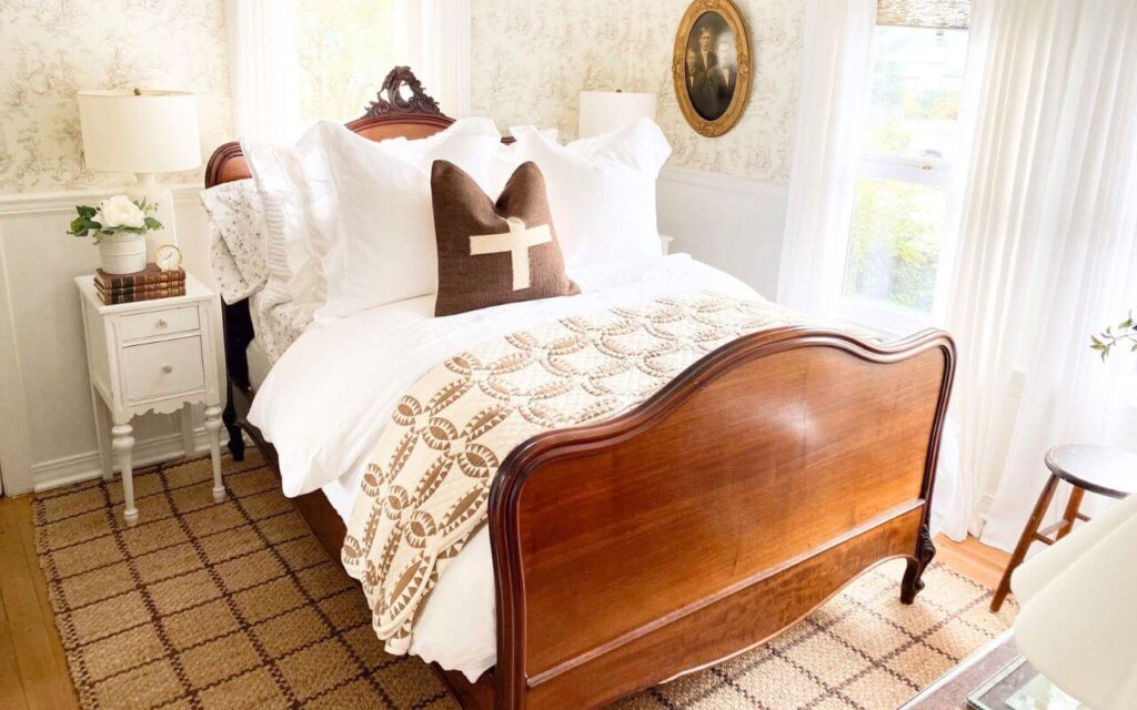 Bedroom with vintate style quilt, white bedding, and jute grid rug.