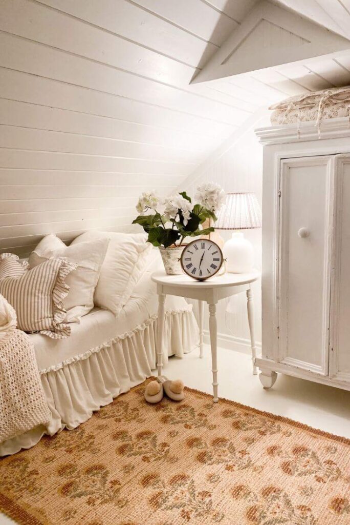 Cottage nook with jute rug, slipper chair, and bedside table with hydrangeas.