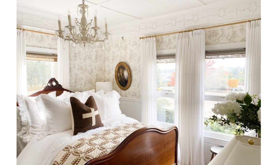 Pleated textured curtains hanging beside toile wallpaper.