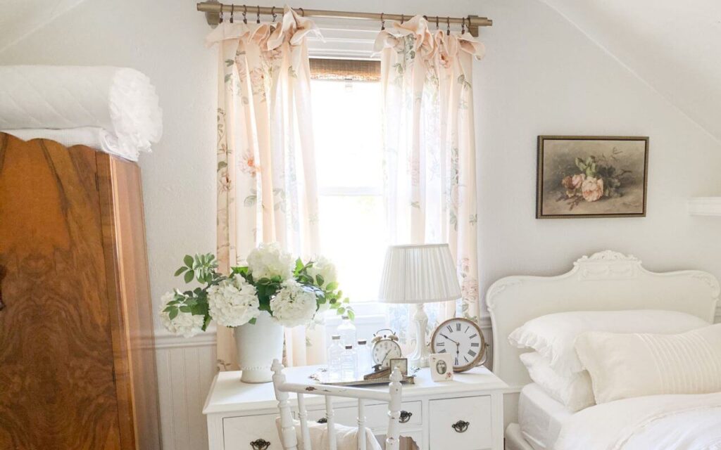 Close up of floral curtains with rose painting over antique bed