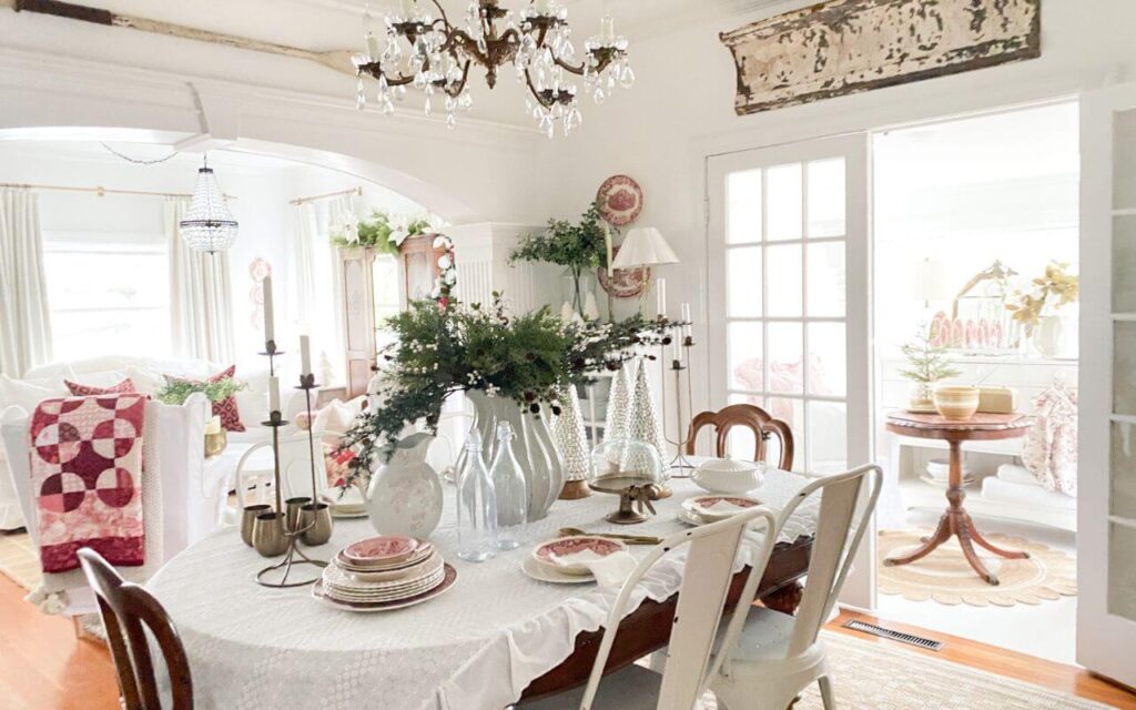Cottage-style Christmas dining room decor connecting to the living room with red quilts and vintage holiday details