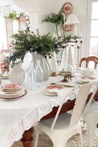 Christmas dining room decor with a cozy cottage feel, featuring a holiday table styled with red transferware and soft neutral layers