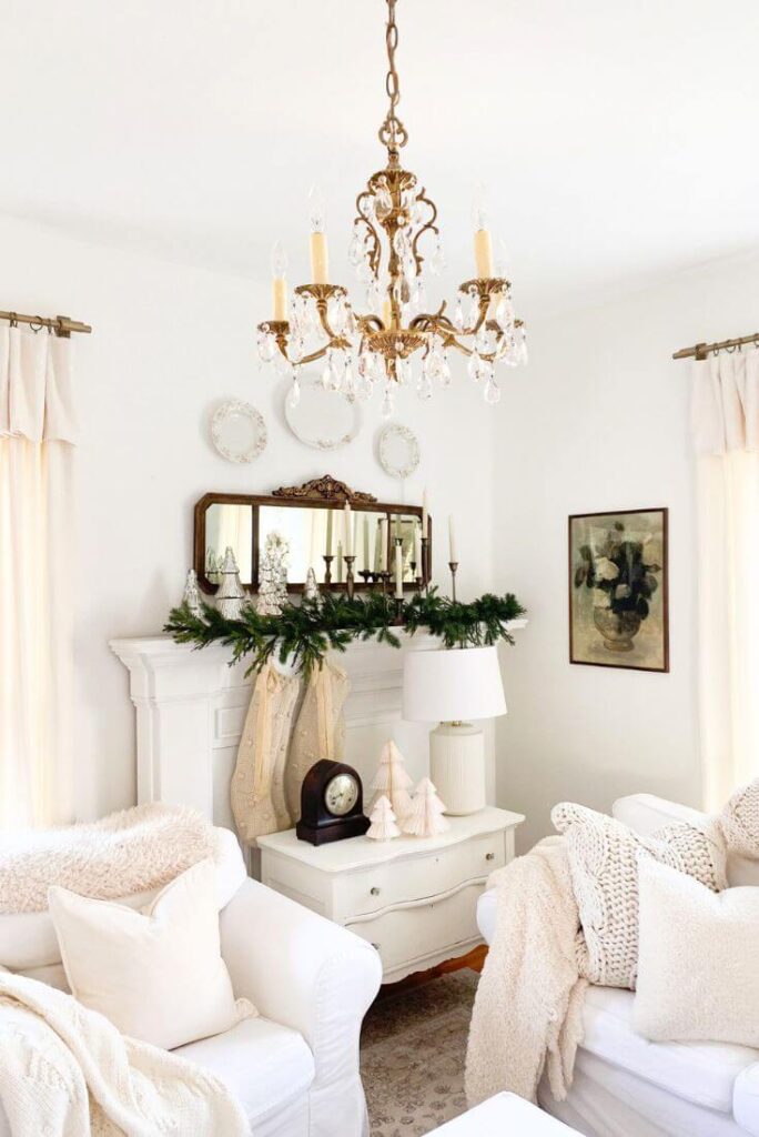 Simple Christmas mantel decor with layered mercury glass trees and garland in a cottage-style living room.