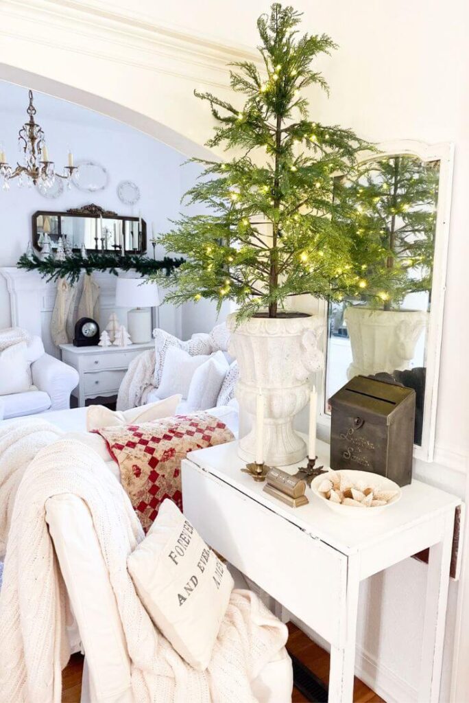 Small cottage entryway styled for Christmas with prelit tree and brass timeless decor on an antique drop leaf table.