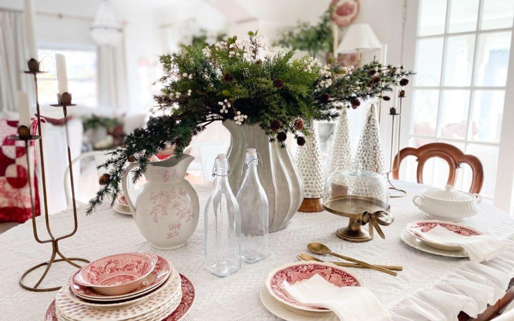 Christmas dining room table styled with red transferware, white linens, and simple holiday greenery
