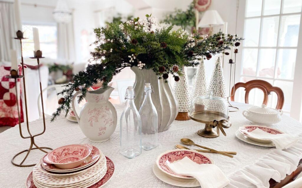 Close-up of Christmas dining room decor with mercury glass trees, brass cake stand, and vintage red transferware