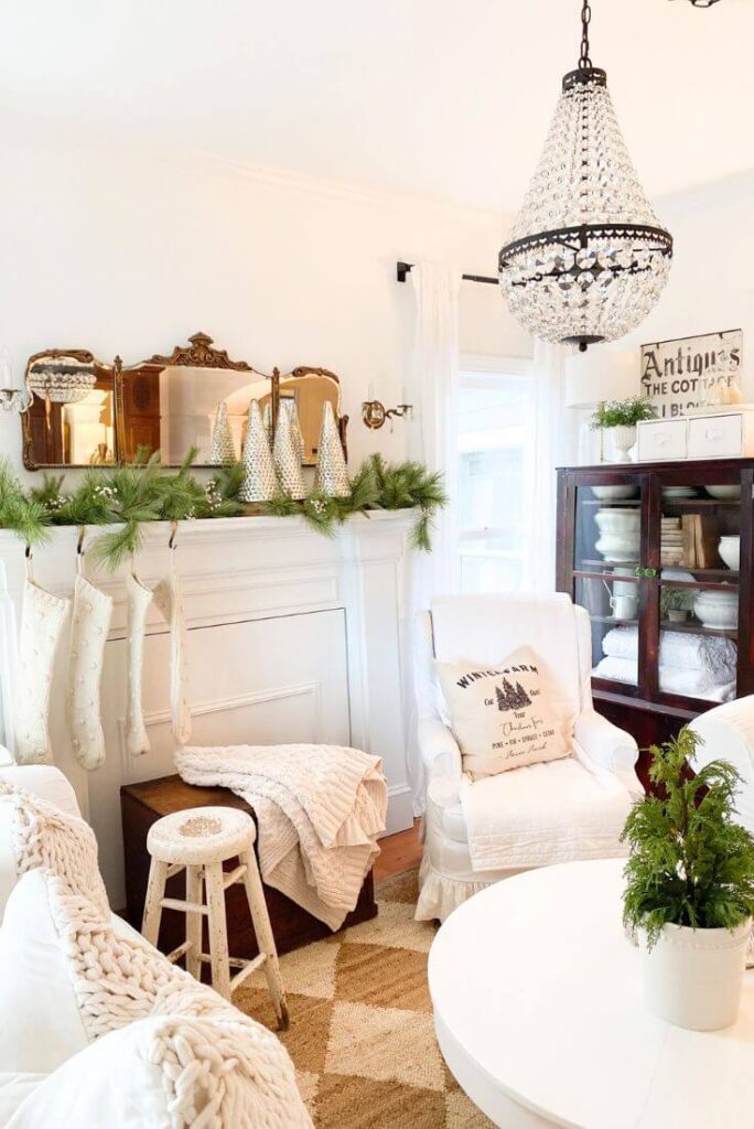 White Christmas mantel styled with three glass mercury glass trees, faux garland and knit stockings in a cottage living room