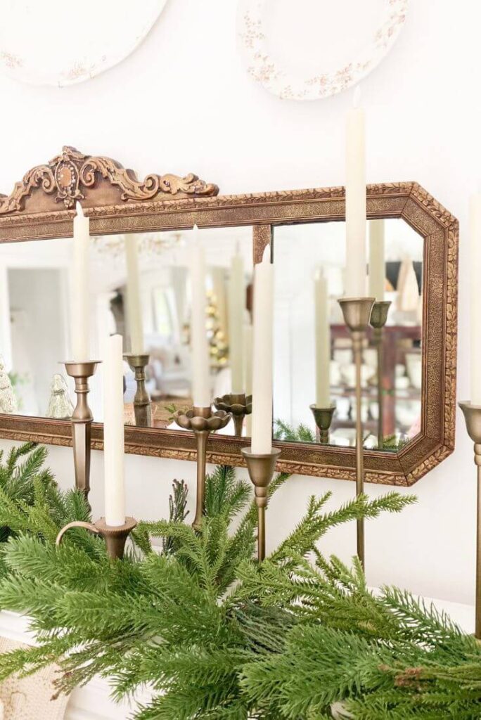 Close-up view of mercury glass trees on a mantel styled with garland and brass candlesticks for a simple Christmas display.