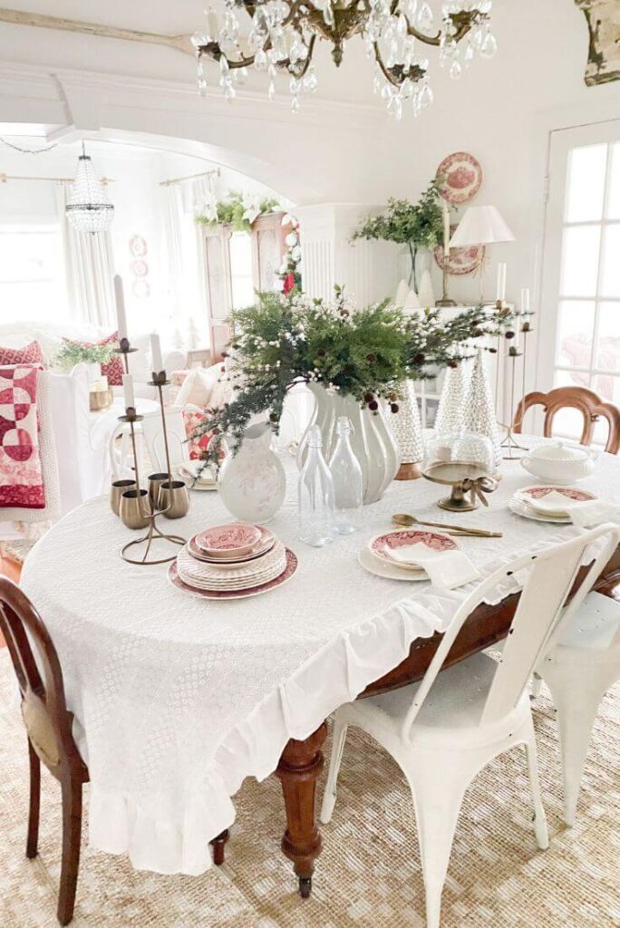 Christmas dining room table styled with red and white transferware, brass accents, and faux greenery for a cozy cottage look