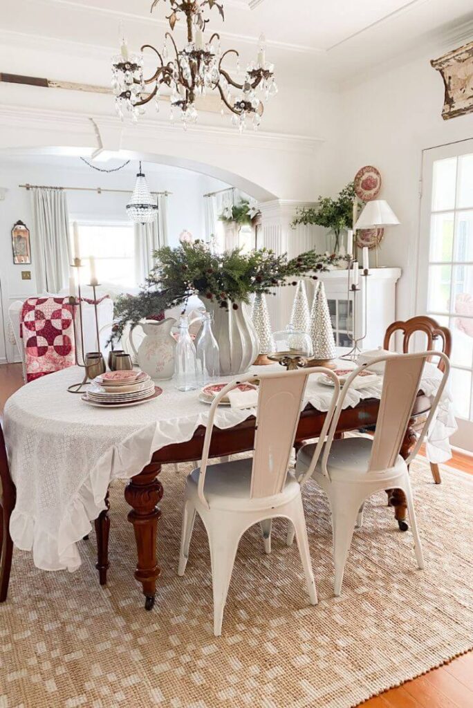 Cozy Christmas dining room decor with vintage red transferware dishes styled on a ruffled tablecloth with mercury glass trees