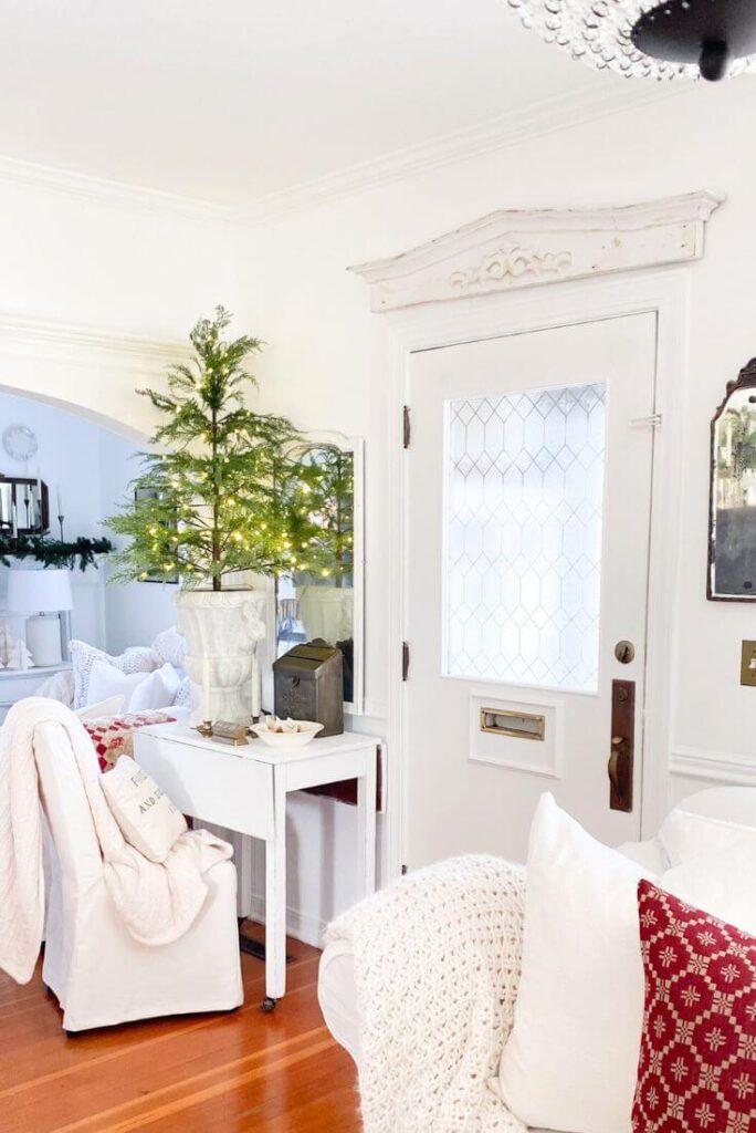 Sparkling pre-lit Christmas tree paired with vintage-inspired decor in a cozy cottage Christmas entryway.