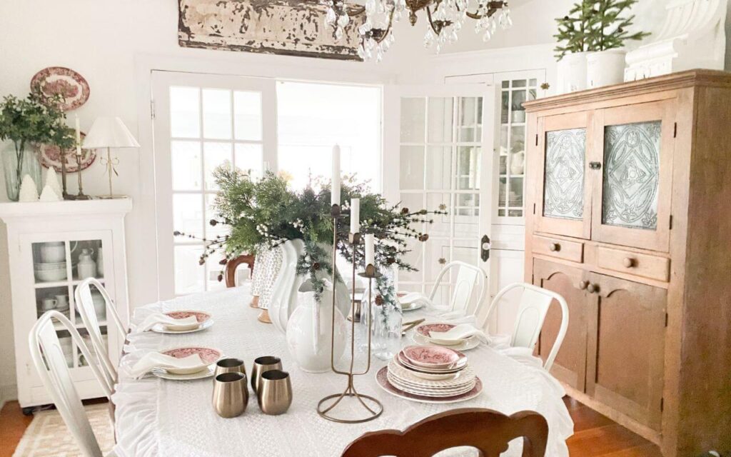 Neutral Christmas dining room with a ruffled tablecloth, vintage red dishes, and mercury glass trees
