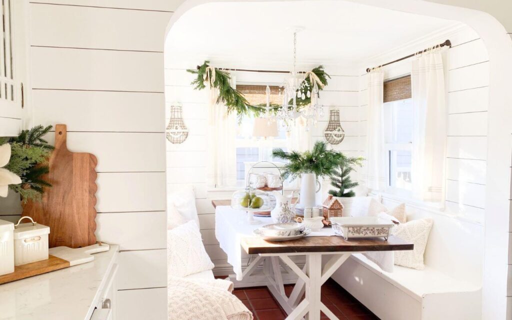 Cozy Christmas kitchen nook with transferware dishes, garland, and greenery.
