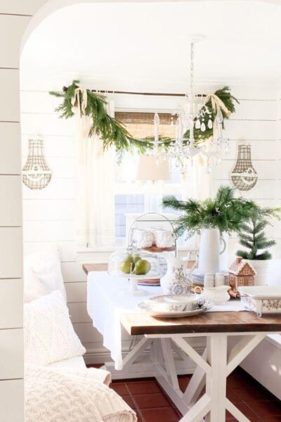 Cozy Christmas kitchen nook with transferware dishes, garland, and greenery.