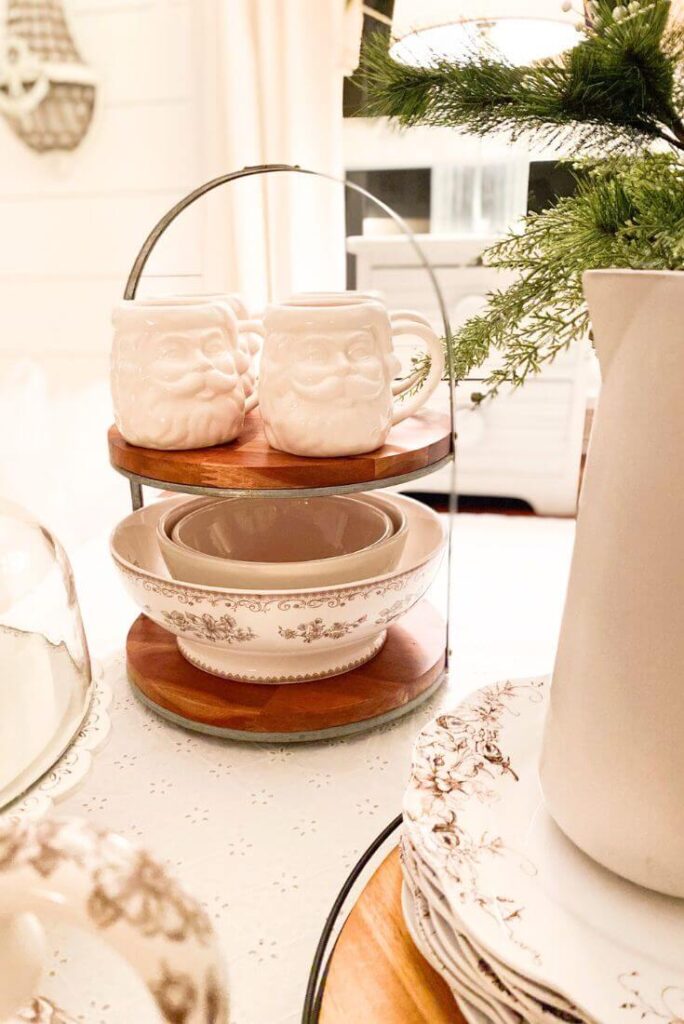 Santa mugs stacked beside Christmas plate set in cozy kitchen nook.