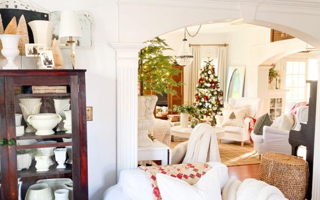 Cottage-style Christmas living room with antique furniture, layered quilts, and simple red accents