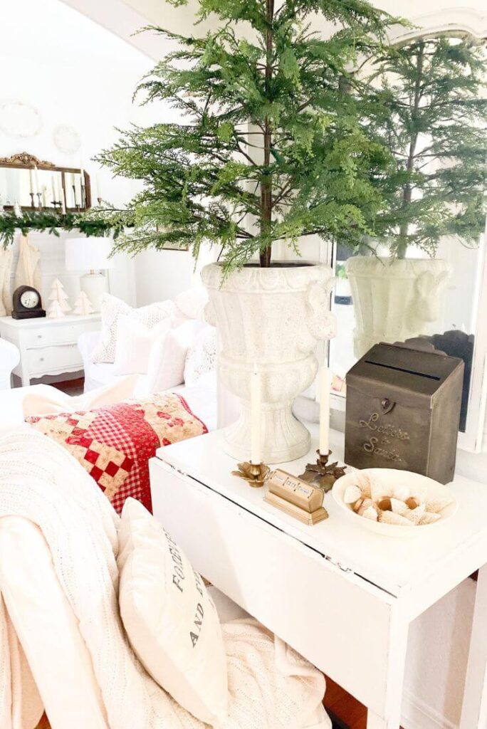 Close-up of holiday vignette with brass accents, greenery, and soft winter lighting in a cottage-inspired entryway.