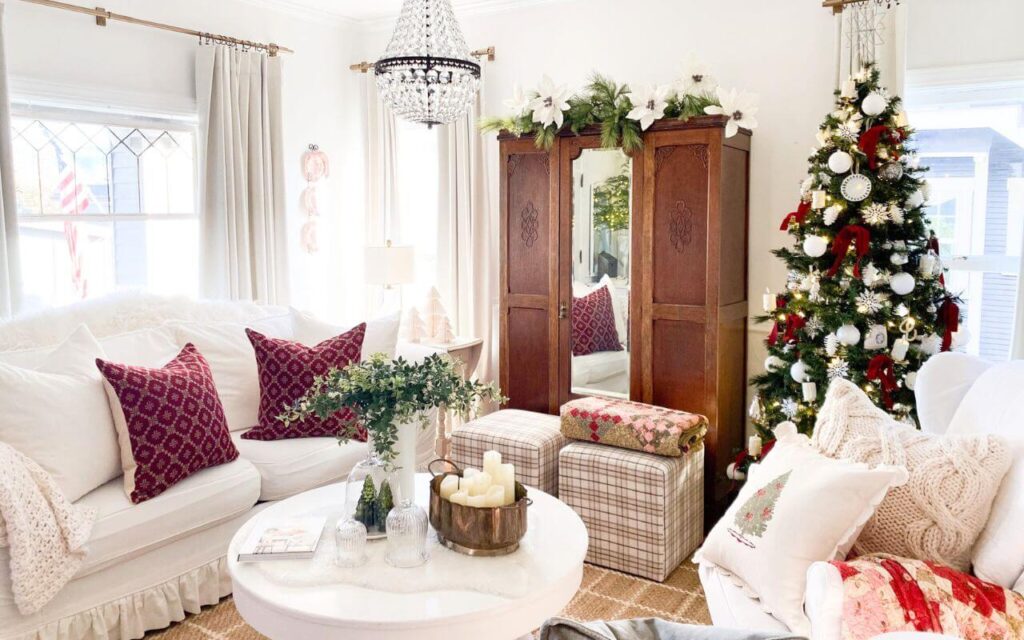 Christmas living room decor with a neutral sofa styled with red holiday pillows, vintage accents, and soft seasonal layers