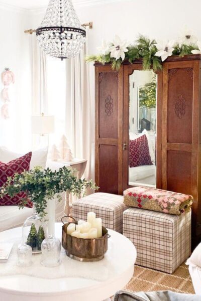 Christmas living room decor with a neutral sofa styled with red holiday pillows, vintage accents, and soft seasonal layers