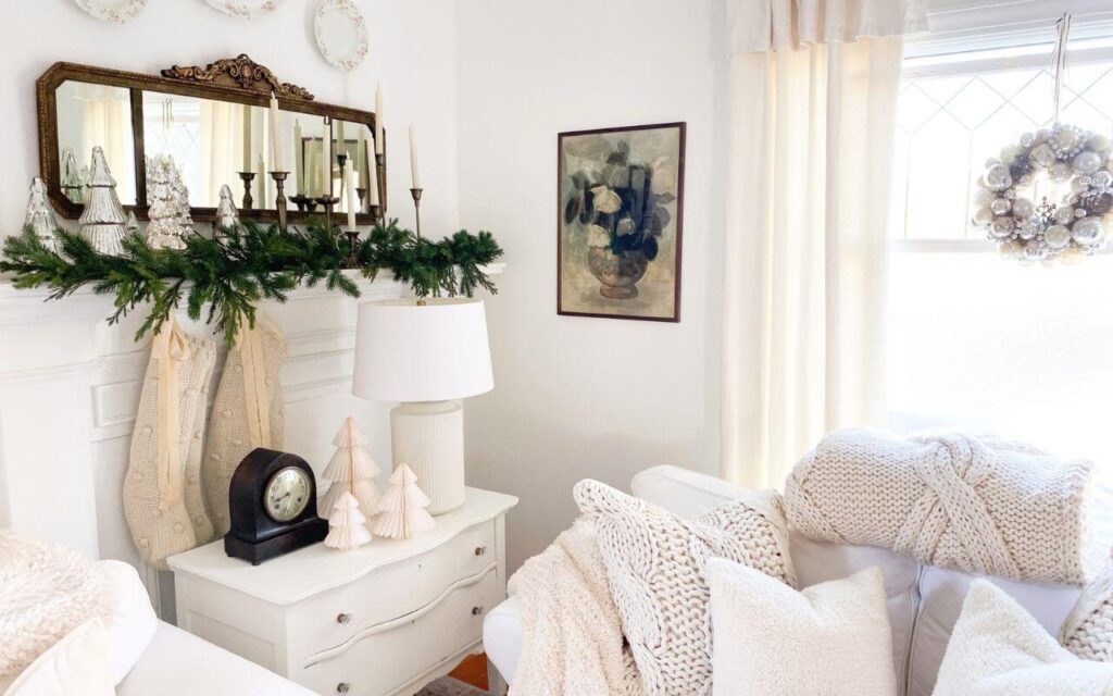 Side table next to the living room fireplace decorated with greenery and Christmas accents for a cozy holiday look.