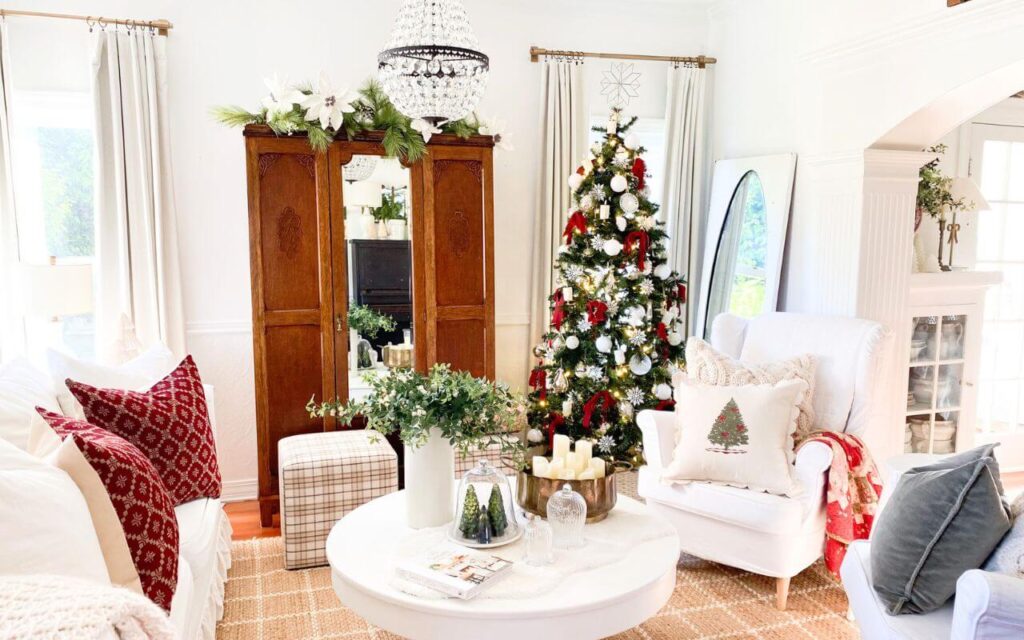 Neutral Christmas living room decor featuring a decorated tree with red velvet bows and vintage ornaments