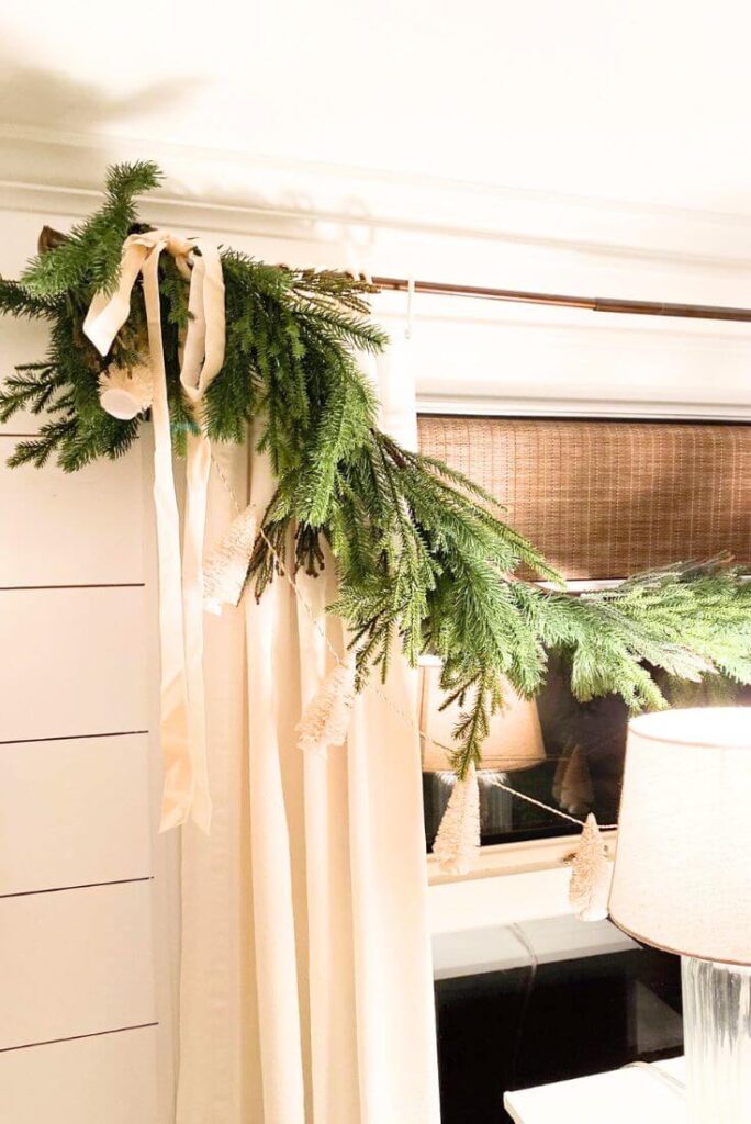 Evergreen garland with ivory velvet ribbon in neutral Christmas kitchen.