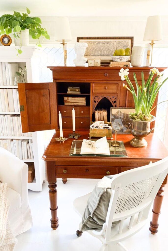 Cottage-style office space with layered antiques and practical window solutions