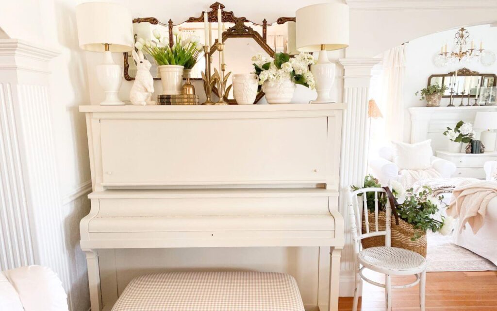 Painted upright piano styled with vintage mirror, lamps, and cottage decor