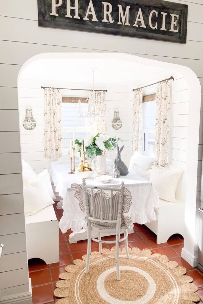 Cozy kitchen nook with ruffled table cloth and floral curtains