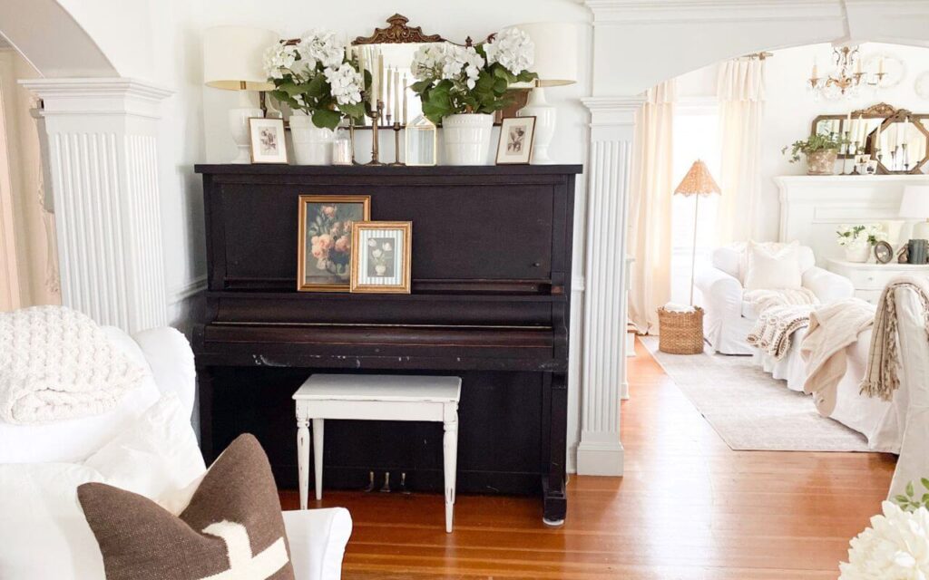 Before photo of an upright piano with dark stain and styled with vintage finds