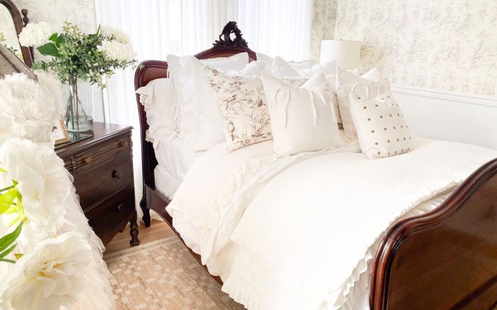 White ruffled bedding and vintage wood bed in a cottage-style bedroom
