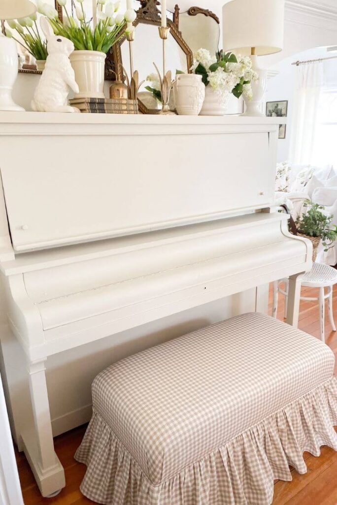 Close up view of a painted piano with a gingham ruffled bench.