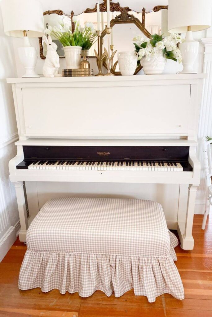 Painted white piano decorated with brass accent candelabras and spring decor.