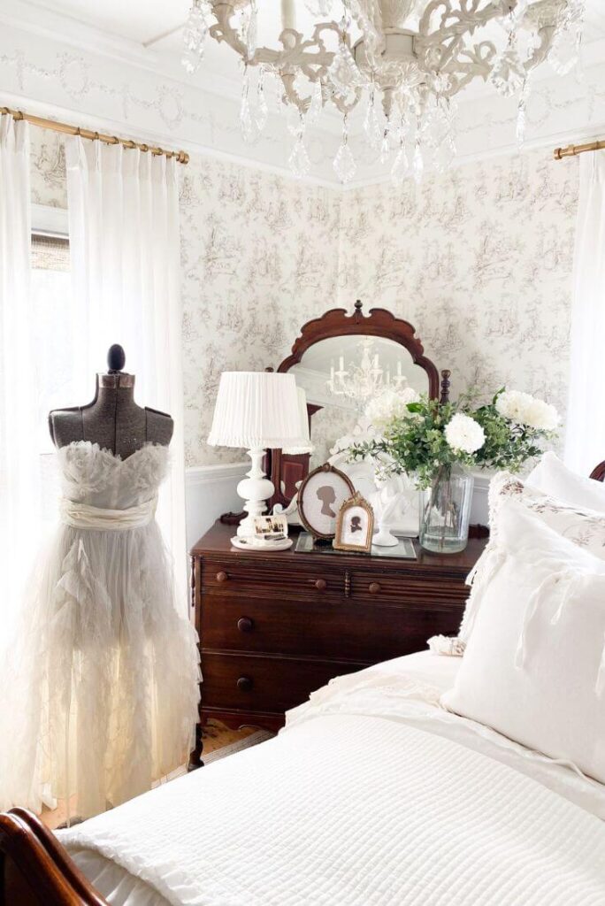 Antique wood dresser and pleated lampshade in softly styled cottage bedroom