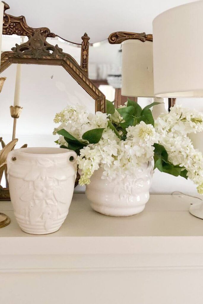 Faux lilacs arranged in vintage white pot.