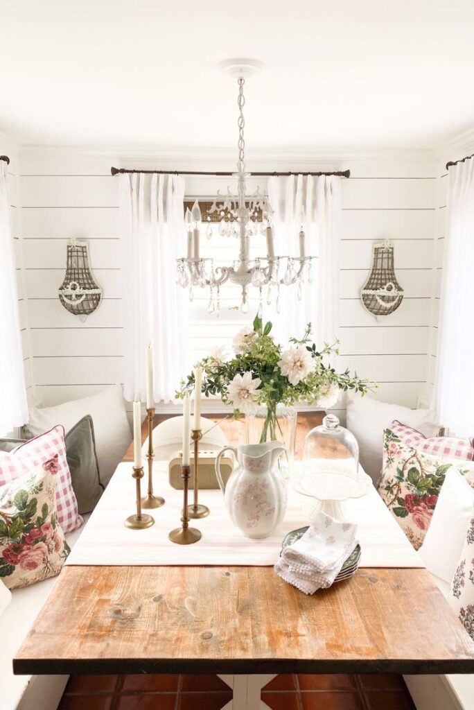 Pink cottage decor with floral arrangement, brass candlesticks, and vintage pink pitcher