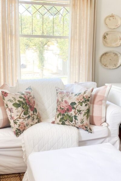 Pink cottage decor with floral pillows and gingham accents on white slipcovered furnitures